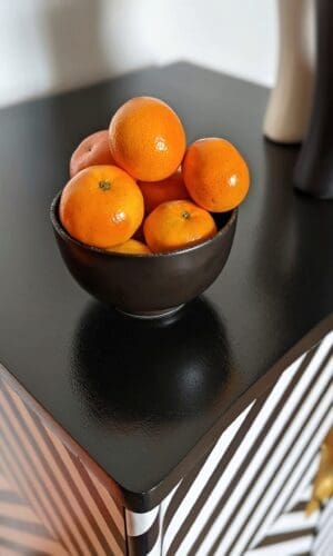 Top view of black and white striped cabinet showing shiney black finish and a bowl or oranges