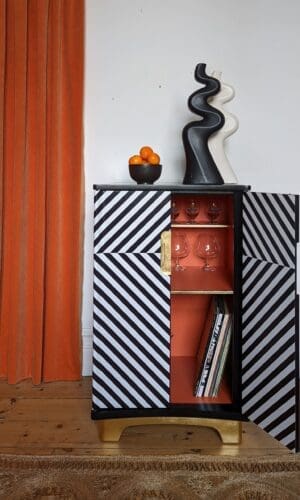 Front view of black and white striped cabinet with one door open showing orange interior
