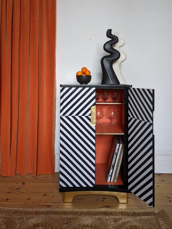 Front view of black and white striped cabinet with one door open showing orange interior