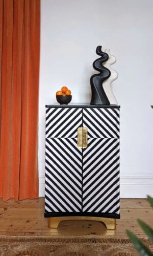 Main view of black and white op-art style cabinet with orange curtain in background