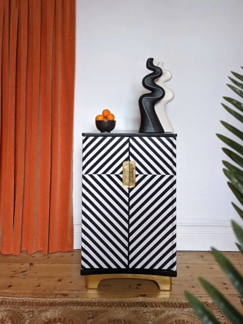 Main view of black and white op-art style cabinet with orange curtain in background