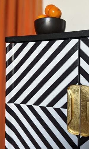 Close up view of gold leaf recessed handles to black and white op-art style cabinet doors