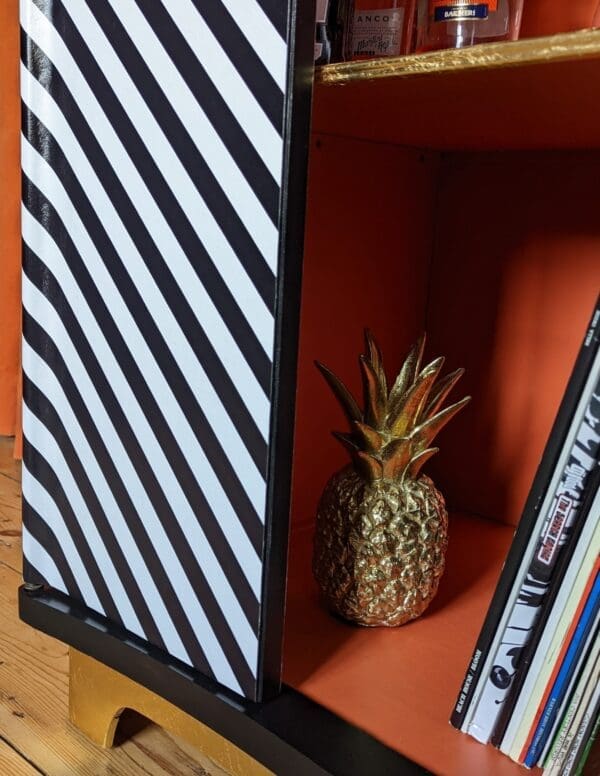 Close up view showing orange interior of cabinet with vinyl records and a gold pineapple