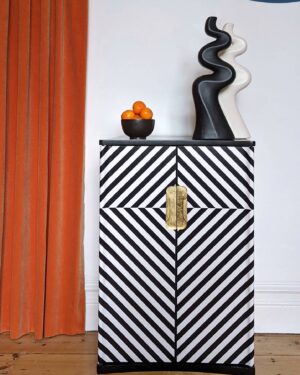 Front view of black and white striped cabinet with gold plinth and handles
