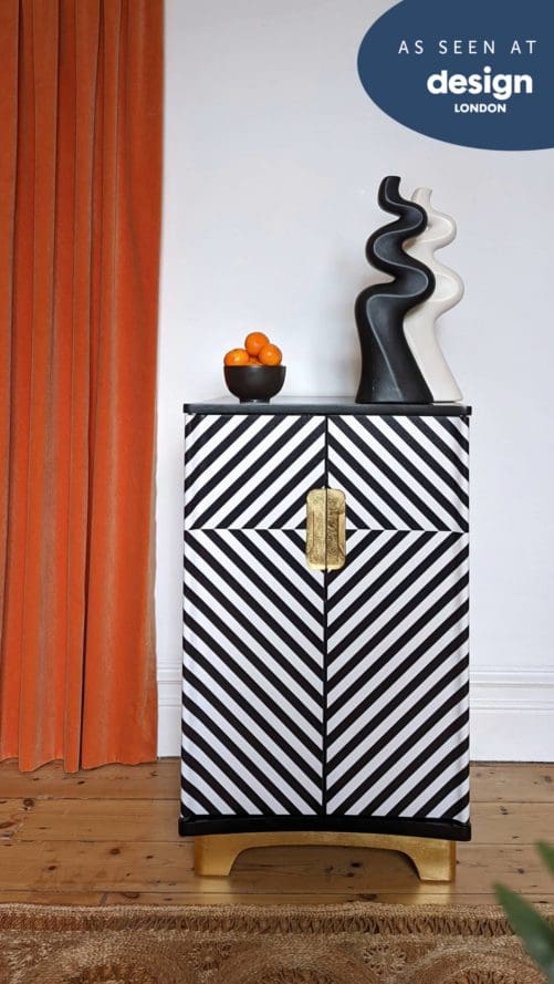 Front view of black and white striped cabinet with gold plinth and handles
