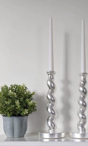Silver barleytwist candlesticks on mantlepiece with plant in pot