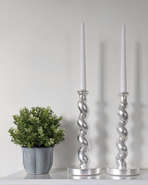 Silver barleytwist candlesticks on mantlepiece with plant in pot