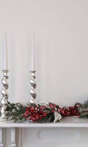 Silver barleytwist candlesticks on mantlepiece with Christmas garland