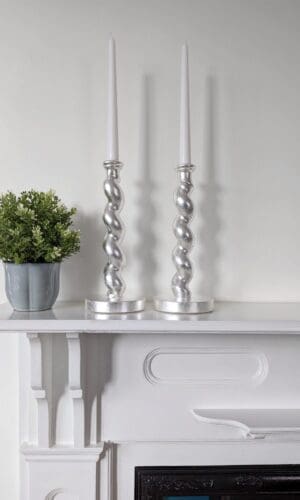 Silver barleytwist candlesticks on mantlepiece with plant in pot