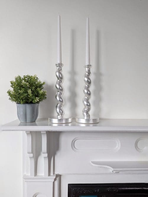 Silver barleytwist candlesticks on mantlepiece with plant in pot