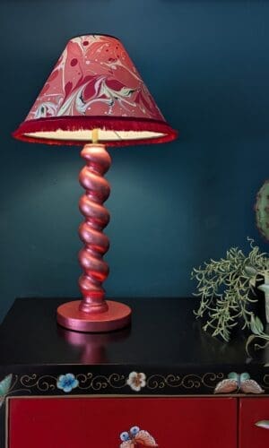 metallic red twist lamp with red marbled shade against dark teal background
