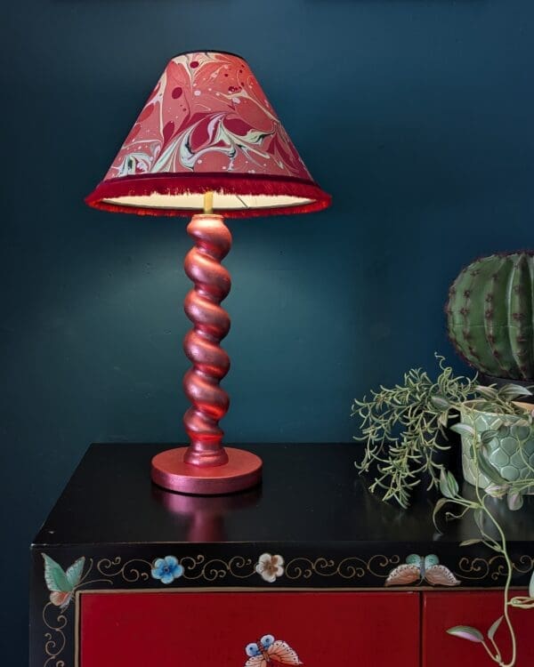 metallic red twist lamp with red marbled shade against dark teal background