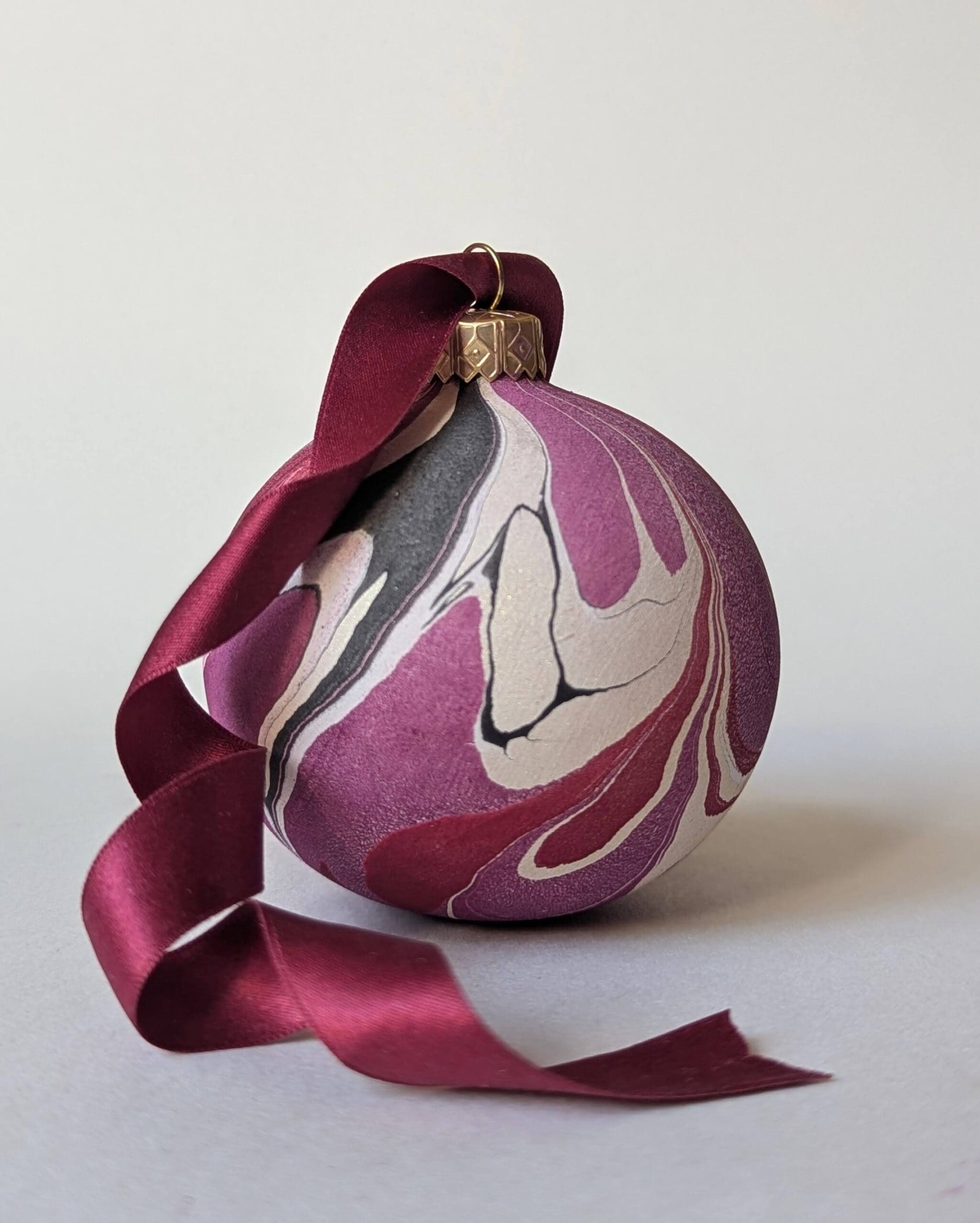 cherry red marbled bauble with dark red trailing ribbon