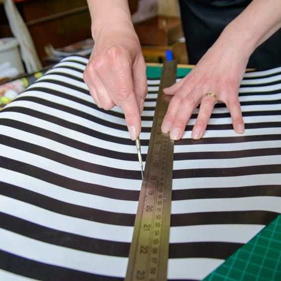 Cutting black and white striped paper with a scalpel and steel ruler square