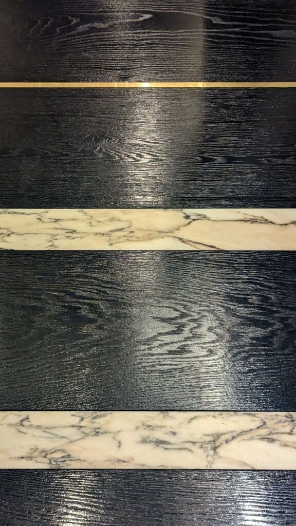 Black wood floor inlaid with white marble and brass