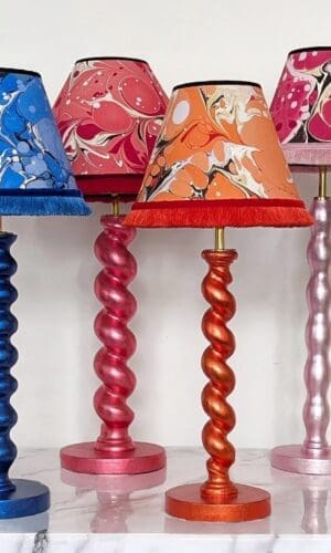 colourful metallic lamps in barley twist and bobbin style in purple, blue, red, orange, pink and green with matching marbled lampshades with fringe trim.
