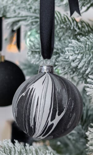 Black and white mabrled Christmas bauble on a tree with a black bauble