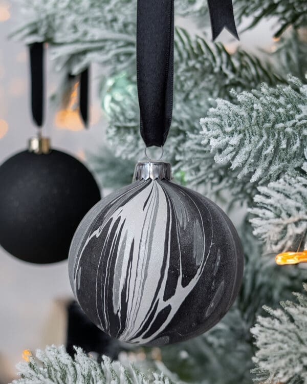 Black and white mabrled Christmas bauble on a tree with a black bauble